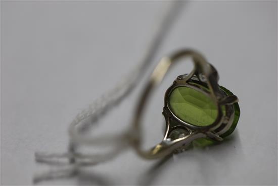A mid 20th century 9ct white gold and oval cut peridot ring with diamond set shoulders, size M.